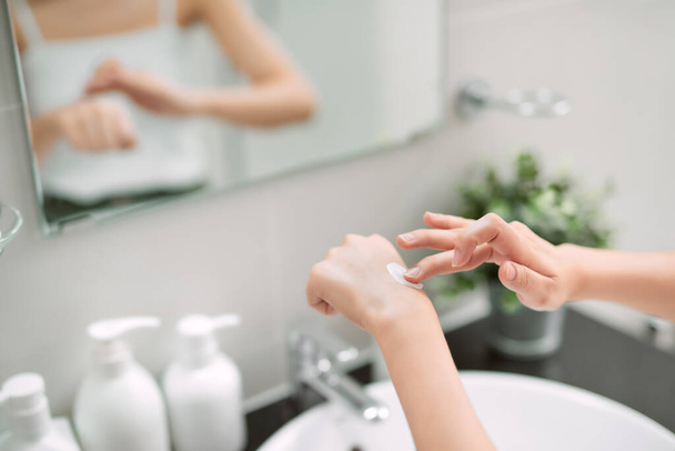 Testgondozás. Nő alkalmazása hidratáló kézkrém kézre és körmökre zuhany után. - Fotó, kép