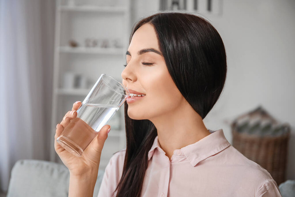 Красива молода жінка п'є воду вдома
 - Фото, зображення