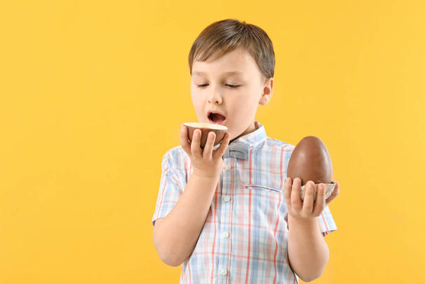 Cute little boy with sweet chocolate eggs on color background - Photo, Image