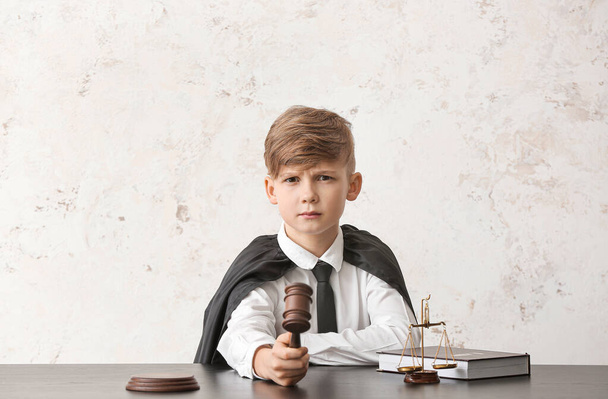 Portrait of little judge sitting at table against white background - Foto, Imagen