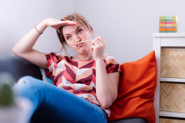 Young girl is sitting on a sofa and doing bored and frustrated gestures - Valokuva, kuva