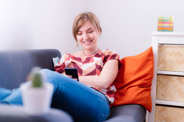 Rubia chica atractiva está acostado en el sofá y mensajes de texto con su novio
 - Foto, imagen