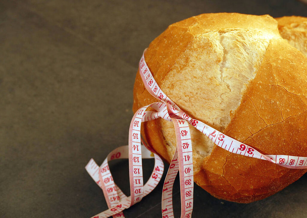 szalag intézkedés csomagolva egy nagy kenyér, kenyér súlya, diéta és kenyér, - Fotó, kép