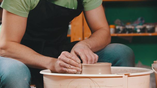Керамика - мастер поднимает стены глиняной чаши руками на гончарный круг
 - Фото, изображение