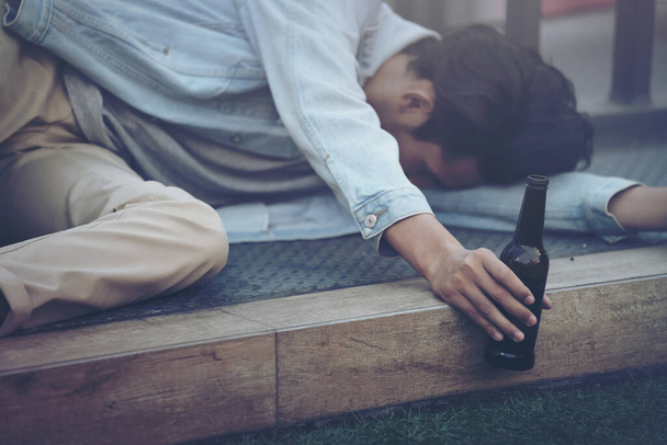 Na het feest. Dronken bebaarde jongeman op straat liggend en slapend na het drinken van veel bier alcohol. - Foto, afbeelding
