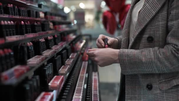 make-up, vrouwelijke shoppers kiezen mooie lippenstift op showcase van professionele make-up winkel tijdens het winkelen, handen dicht - Video