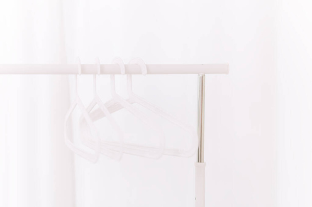 Stilvolle weiße Kleiderbügel auf einem weißen Tresen in einem weißen Raum - Foto, Bild