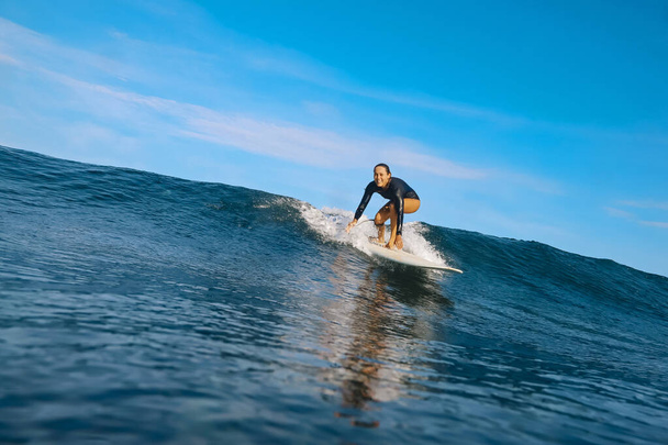 Female surfer on a blue wave at sunny day - 写真・画像