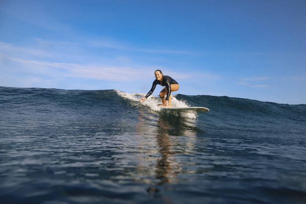 Female surfer on a blue wave at sunny day - Foto, afbeelding