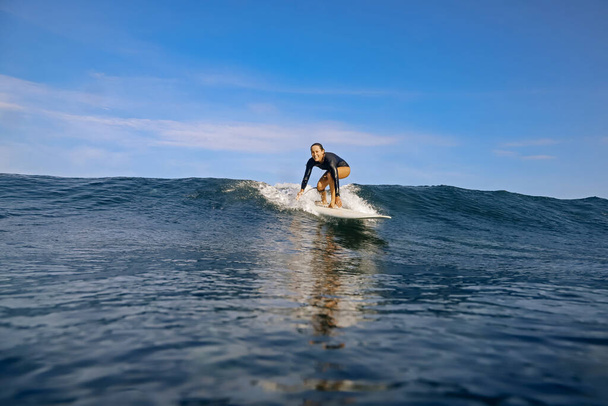 Female surfer on a blue wave at sunny day - Photo, Image