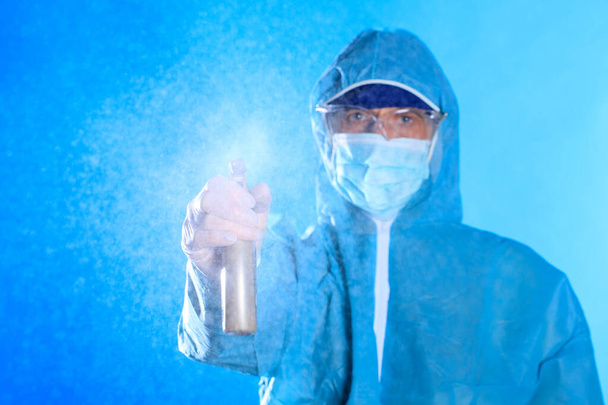 man in a blue full protected suit with disinfectant , conavirus pandemic - Cleaning and Disinfection. Infection prevention and control of epidemic - Photo, Image