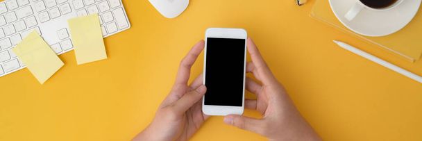 Plan recadré d'un homme tenant smartphone avec dispositif informatique et tasse de café sur fond jaune peut être utilisé pour la bannière
  - Photo, image