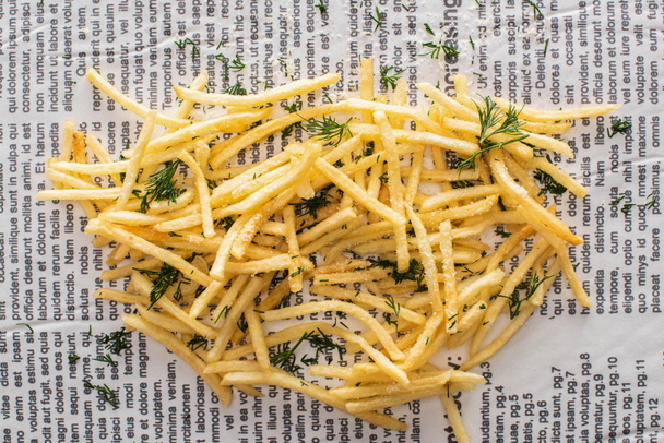 top view of crispy french fries with dill on newspaper - Photo, Image
