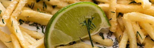 panoramic shot of lime near crispy french fries with dill  - Fotografie, Obrázek