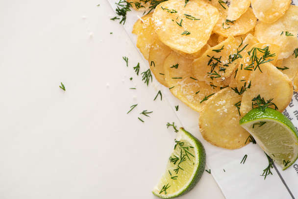 top view of crunchy potato chips with salt near sliced lime on white  - Фото, зображення