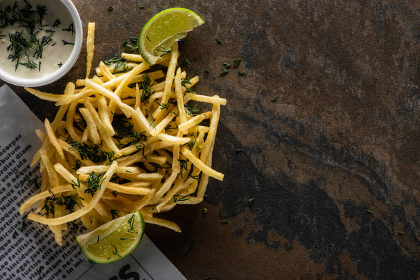 top view of tasty french fries, lime and garlic sauce on marble surface  - Foto, Imagem