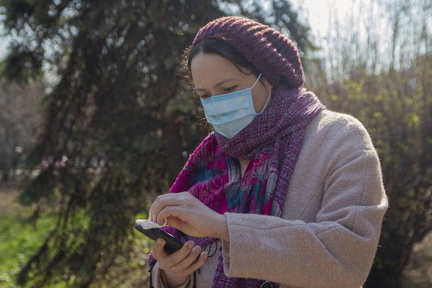 Serious woman in a protective mask with a smartphone. People - Photo, Image