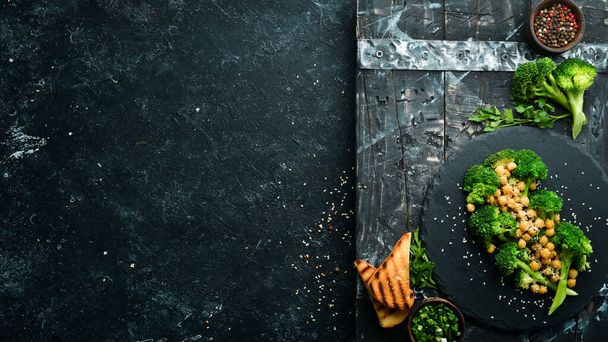 Здоровое питание: брокколи, горох и кунжут на черной каменной тарелке. Вид сверху. Свободное место для текста
. - Фото, изображение