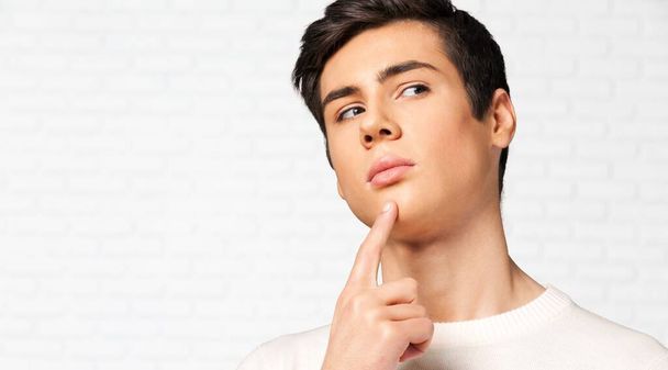 young man in white shirt looking up, on grey background - Foto, imagen