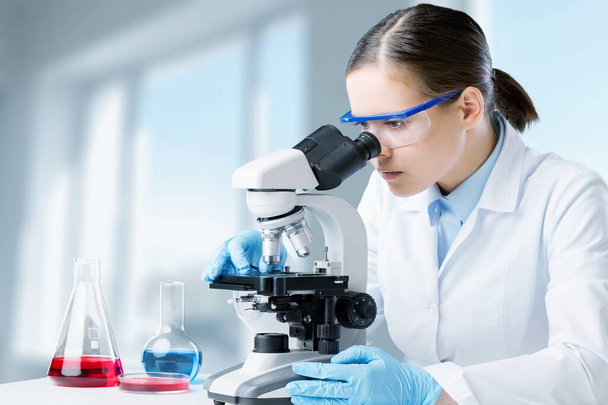 Young woman using microscope in laboratory   - Photo, Image