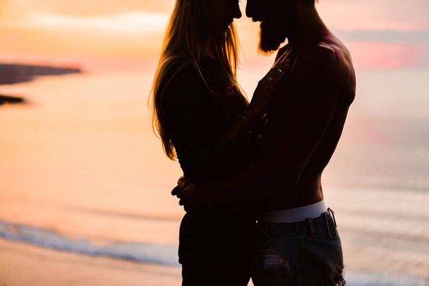 couple in love at sunset on the ocean. mixed couple. - Foto, imagen