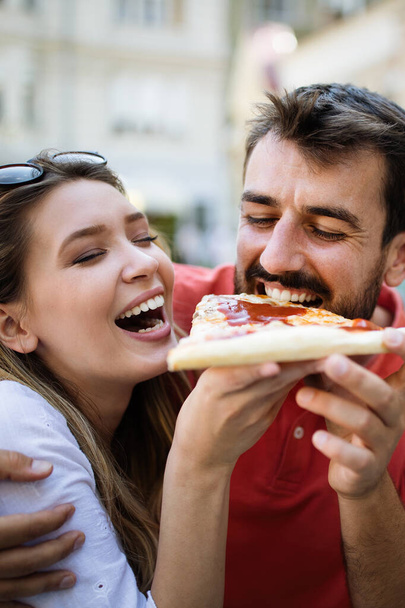 Happy couple laughing and eating pizza, having a great time together - Foto, Imagem