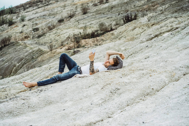 Um jovem na natureza à beira da terra usa um smartphone
 - Foto, Imagem