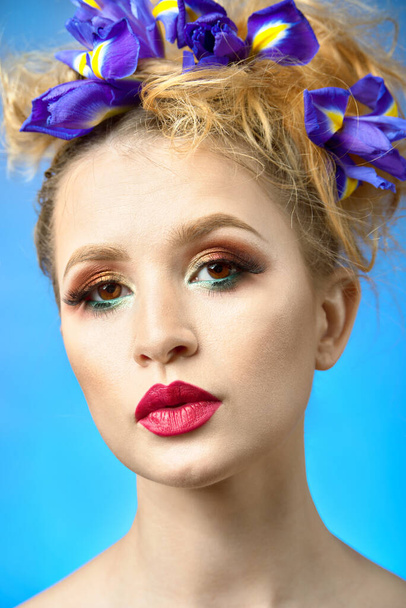 beauty portrait of a beautiful woman with painted lips. in the hairstyle of girl blue flowers iris - Photo, image