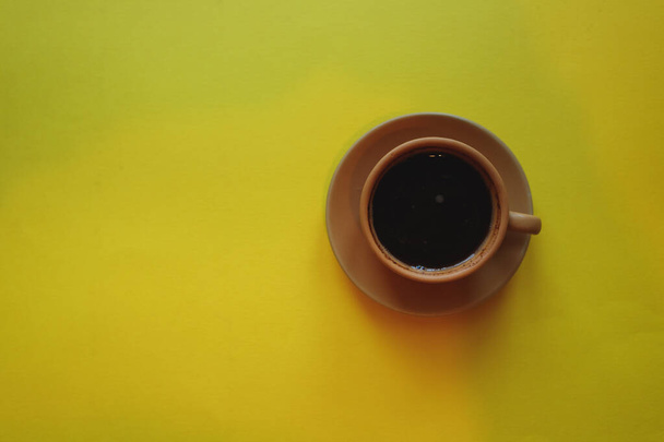 cup of coffee on yellow background with notepad - Foto, Imagem
