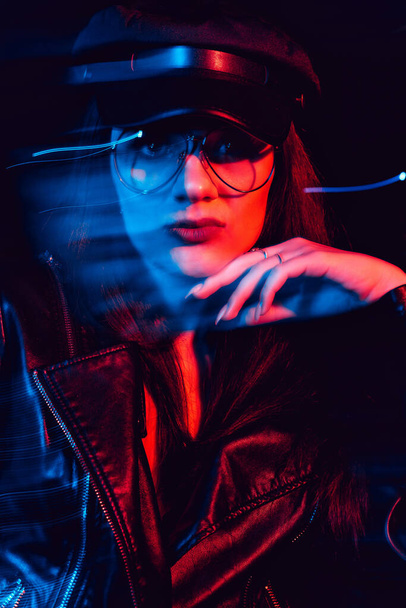 стильний портрет молодої дівчини в окулярах в шкіряній куртці і шапці
 - Фото, зображення