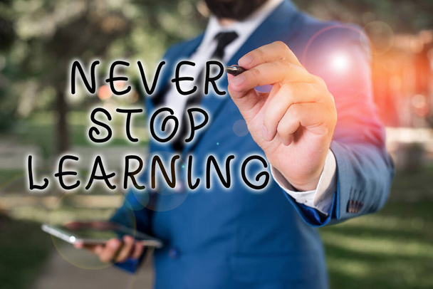 Text sign showing Never Stop Learning. Conceptual photo keep on studying gaining new knowledge or materials Businessman holds laptop and pen pointing into the copy space. - Fotografie, Obrázek