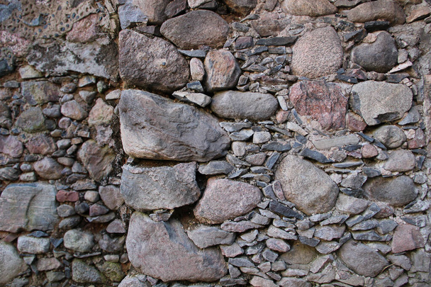 Vieja pared hecha de rocas. Superficie medieval hecha de ladrillos. Textura de una roca vieja pegada con un cemento
. - Foto, Imagen