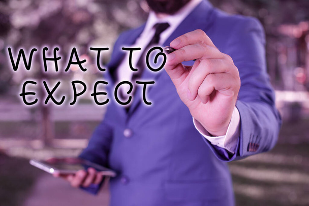 Text sign showing What To Expect. Conceptual photo asking about regard something as likely to happen occur Businessman holds laptop and pen pointing into the copy space. - Photo, Image