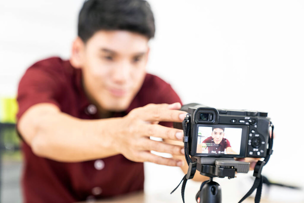 Young Asian male blogger setting up camera for recording live vlog video tutorial session at home. IT blogging or vlogging, social media hobby broadcasting, or online learning course concept. - Foto, imagen
