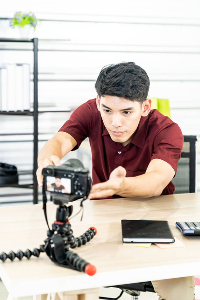 Young Asian male blogger setting up camera for recording live vlog video tutorial session at home. IT blogging or vlogging, social media hobby broadcasting, or online learning course concept. - Foto, imagen