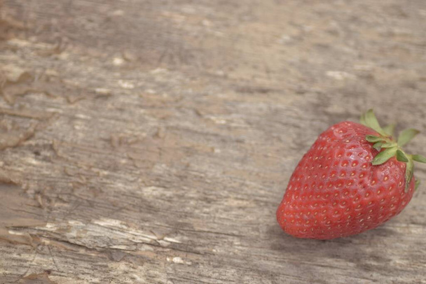 A strawberry on a wooden table during the daytime - Fotografie, Obrázek