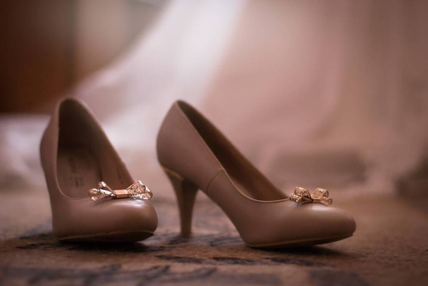 A closeup of high heels with bows on them on the carpet under the lights with a blurry background - Foto, Imagem