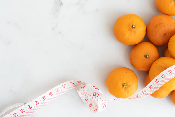 oranssi kääritty mittanauhalla valkoiselle marmoripinnalle. Käsite hedelmien ravitsemus ja ruokavalio elintarvikkeet
. - Valokuva, kuva