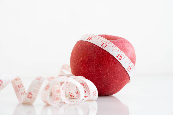 Apple kääritty mittanauhalla valkoisella marmoripinnalla. Käsite hedelmien ravitsemus ja ruokavalio elintarvikkeet
. - Valokuva, kuva