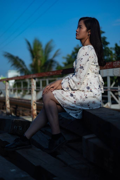 A vertical shot of a Vietnamese girl sitting on an old bridge - Foto, Imagem