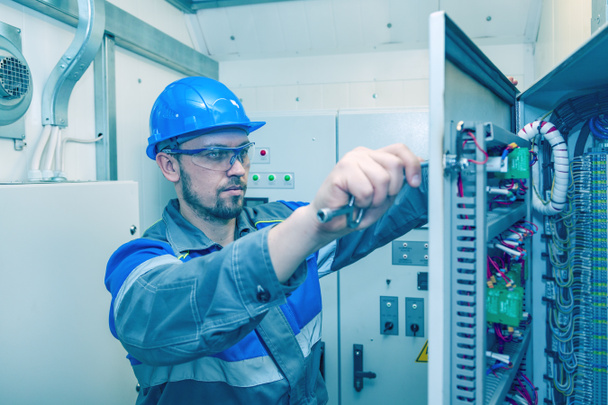 Energy and electricity, electromechanical protective at work with an electric panel, an electrician diagnoses electrical distribution panels in an electrical panel, toned - Photo, image