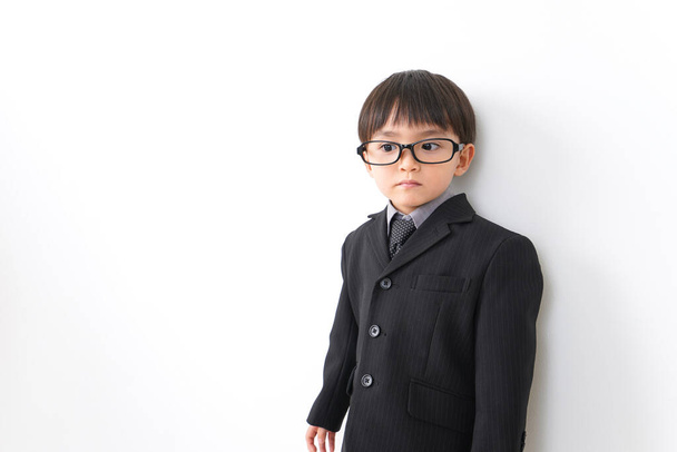 little boy wearing suit and eyeglasses posing in studio on white background - Fotó, kép