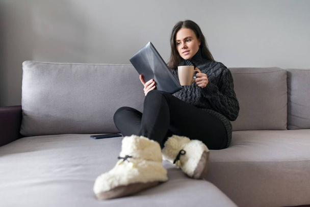 Молодая женщина сидит дома на диване с гаджетами, женщина читает смартфон с цифровым планшетным смартфоном, смотрит блоги, видео, социальные сети, копировать спаз
 - Фото, изображение