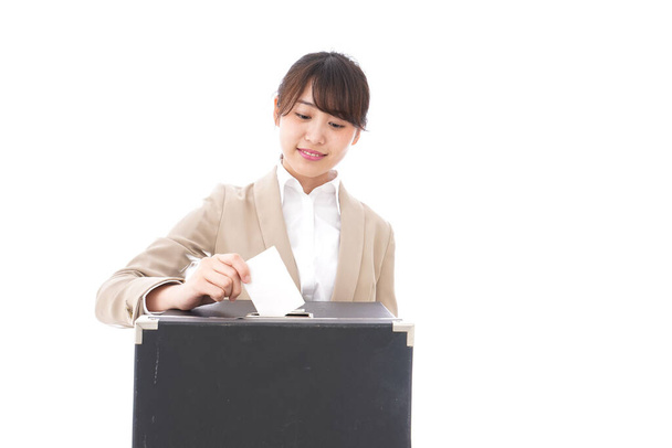 Ασιάτισσα επιχειρηματίας ρίχνει την ψήφο της στο κουτί απομονωμένη σε λευκό φόντο - Φωτογραφία, εικόνα