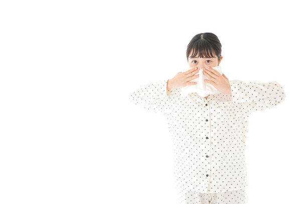 Mujer joven asiática en pijama con gripe aislada sobre un fondo blanco
 - Foto, imagen