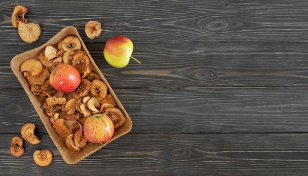 乾燥したリンゴと熟したリンゴを暗い木製のテーブルの上に置きます。トップビュー、テキストのためのスペース。伝統的な民間飲料を作るための成分-コンポート(煮込みアップルドリンク).健康的なフルーツドリンク - 写真・画像