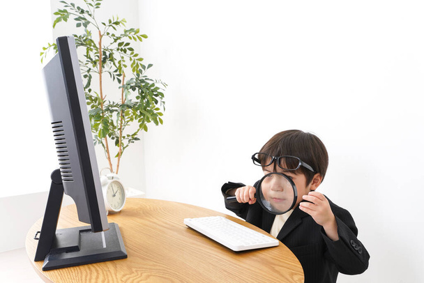 malý chlapec studuje pomocí desktopové PC a lupy  - Fotografie, Obrázek