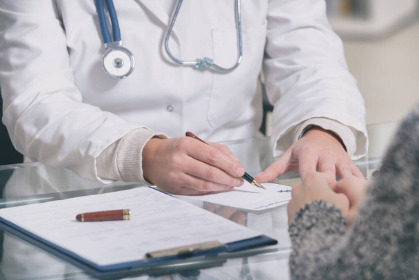 Donna medico scrive prescrizione al paziente sul tavolo da lavoro
 - Foto, immagini