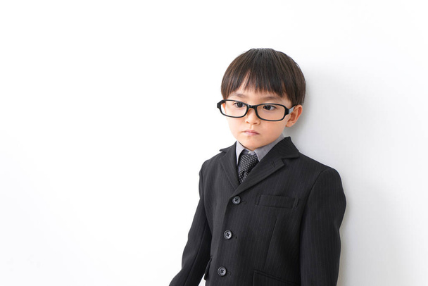 little boy wearing suit and eyeglasses posing in studio on white background - Zdjęcie, obraz
