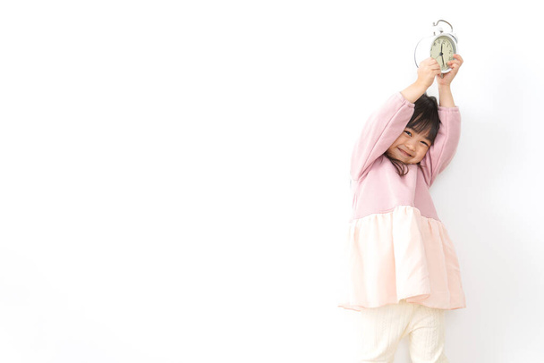маленька дівчинка тримає будильник
 - Фото, зображення